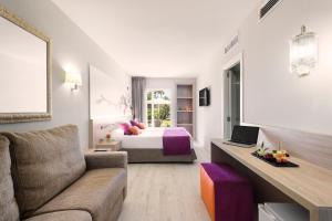 a hotel room with a bed and a couch at Garden Holiday Village - Adults Only in Playa de Muro