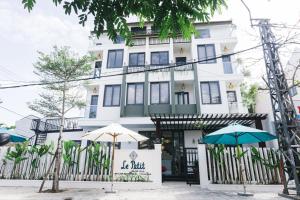 a white building with two umbrellas in front of it at Le Petit Villa Hoi An in Hoi An