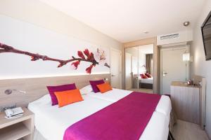 1 dormitorio con 1 cama grande con almohadas moradas y naranjas en Garden Holiday Village - Adults Only, en Playa de Muro