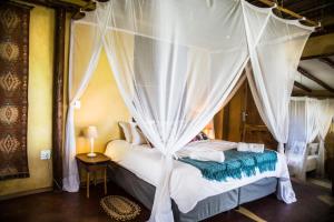 a bedroom with a bed with a canopy at Tofinho Beach House in Praia do Tofo
