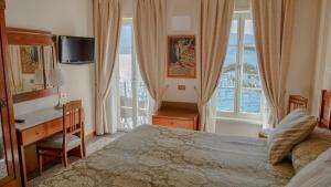 a bedroom with a bed and a desk and a window at Hotel Du Lac in Gargnano