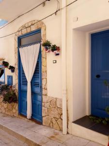 eine blaue Tür mit einem Vorhang an der Seite eines Gebäudes in der Unterkunft Casa vacanze Al porticciolo romantico in Trappeto