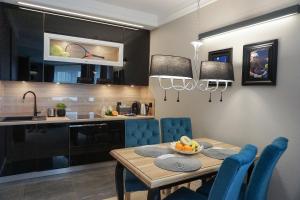 a kitchen and dining room with a table and blue chairs at AGA Tenis Apartments by Radwańska in Kraków