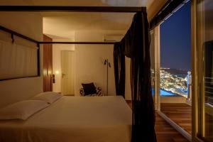 a bedroom with a bed and a balcony with a view at Nefeles Luxury Suites in Fira