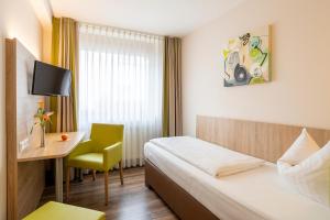 Una habitación de hotel con una cama, un escritorio y una silla. en Kleefelder Hof, en Hannover