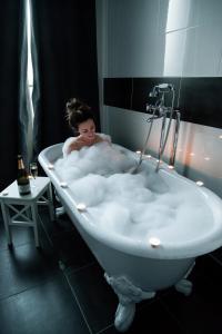 a woman is sitting in a bath tub at La Demeure des Sacres in Reims
