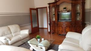 sala de estar con 2 sofás blancos y TV en VAL D'ORCIA DELUXE 1 ELEGANTE CASA immersa nel verde con WiFi, giardino e parcheggio, en San Giovanni dʼAsso