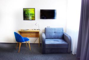 een kamer met een blauwe stoel en een bureau bij S7 Hotel in Kielce
