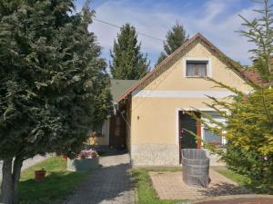 Una casa amarilla con un árbol delante. en Gergely Vendégház, en Zirc