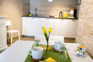una mesa con dos tazas y un jarrón con flores amarillas en Daniela Camere, en Sirolo