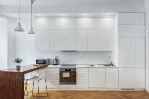 cocina con armarios blancos y encimera de madera en Bednarska Old Town Apartment, en Varsovia