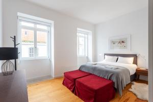 a white bedroom with a bed and a red bench at FLH Chiado Amazing Flat in Lisbon