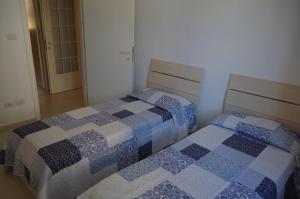 a bedroom with two beds with blue and white quilts at Scerne Holiday Service Adina in Scerne