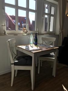 a white table with two chairs and two bottles on it at Inselresidenz Strandburg Apartment 209 in Juist