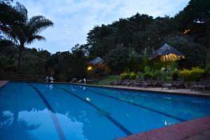 a swimming pool with chairs and umbrellas in a resort at Masai Lodge in Nairobi