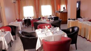 a dining room with white tables and red chairs at Hotel Mansel in Yaoundé