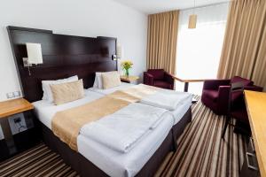 pokój hotelowy z dużym łóżkiem i krzesłami w obiekcie Parkhotel Plzen Congress Center w Pilznie