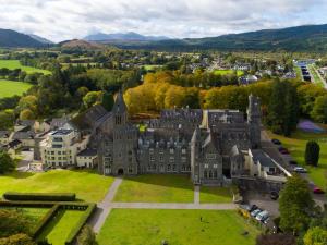 an aerial view of a castle with a green lawn at Loch Ness Moat House Apartments in Fort Augustus