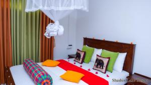 a bedroom with a large bed with colorful pillows at Shashin Lake Resort in Dambulla