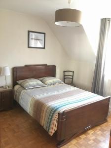 een slaapkamer met een groot bed met een houten hoofdeinde bij Calme et lumière à proximité de la Vieille Ville de Boulogne sur mer in Boulogne-sur-Mer