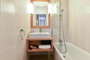 a bathroom with a sink and a mirror and a tub at Résidence Pierre & Vacances Premium Port Prestige in Antibes