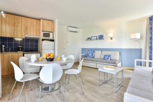 a kitchen and a living room with a table and chairs at Résidence Pierre & Vacances Premium Port Prestige in Antibes