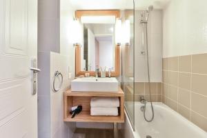 a bathroom with a sink and a tub and a mirror at Résidence Pierre & Vacances Premium Port Prestige in Antibes