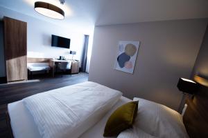 a bedroom with a bed and a room with a desk at V Boutique Hotel Böblingen in Böblingen