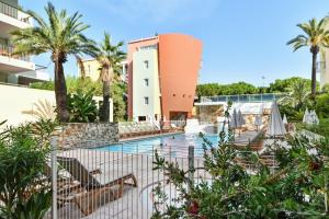 a pool at a resort with chairs and palm trees at Résidence Pierre & Vacances Premium Port Prestige in Antibes