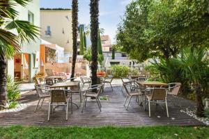 an outdoor patio with tables and chairs and trees at Résidence Pierre & Vacances Premium Port Prestige in Antibes
