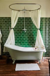y baño verde con bañera con cortina. en Manoir Laurette en Saint-Martin-Petit