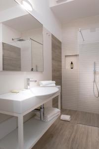 a white bathroom with a sink and a mirror at YOUMAMI Suite Hotel in Giulianova