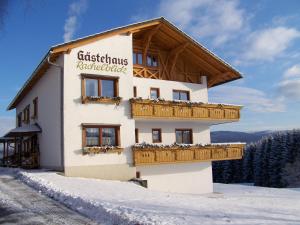 a building with a sign on it in the snow at Gästehaus Rachelblick in Frauenau