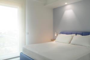 朱利亚诺瓦YOUMAMI Suite Hotel Wellness&Spa的一张白色的床，配有白色的枕头和一扇窗户