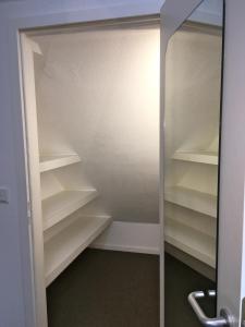 a closet with white shelves and a glass door at Studio Emilie in Detmold