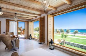 a living room with large windows and a view of the ocean at Mitsis Selection Blue Domes in Kardamaina