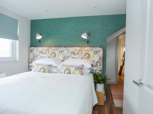 a bedroom with a white bed with a colorful headboard at Burton Apartment in Trearddur