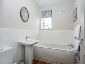 a white bathroom with a sink and a bath tub at Burton Apartment in Trearddur