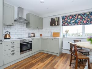 a kitchen with white cabinets and a table with chairs at Burton Apartment in Trearddur +15 photos