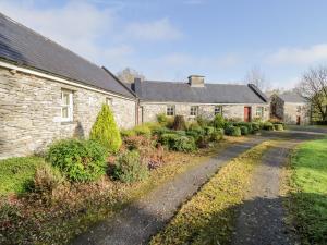 una vieja casa de piedra con una carretera delante de ella en Cluaincarraig, en Kilkelly