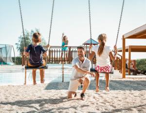 a man and two children playing on a swing at Mitsis Selection Blue Domes in Kardamaina