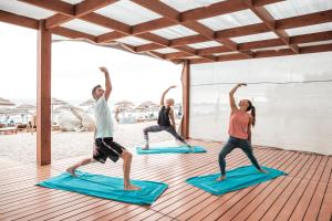 a group of people doing yoga on mats on the beach at Mitsis Selection Blue Domes in Kardamaina