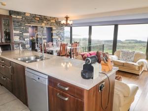 a kitchen with a sink and a living room at Ocean Sail House in Dungloe