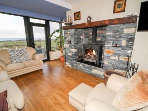 a living room with a stone fireplace at Ocean Sail House in Dungloe