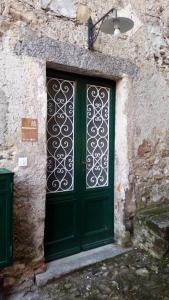 una porta verde con un cancello di metallo su un edificio in pietra di B&B Val Valerna a Lezzeno