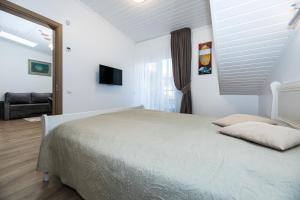 ein weißes Schlafzimmer mit einem Bett und einem TV in der Unterkunft Toro apartamentai - Centras in Palanga