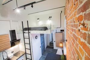 a room with a bed on a ladder and a brick wall at БЕСКОНТАКТНОЕ ЗАСЕЛЕНИЕ - GoldenRingApartments - Flour Mill Loft in Yaroslavl
