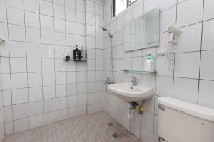 La salle de bains est pourvue de carrelage blanc, d'un lavabo et d'un miroir. dans l'établissement 花蓮嵐海民宿, à Xincheng