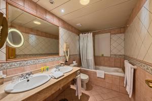a bathroom with two sinks and a tub and a toilet at Grand Hotel Gozo in Għajnsielem