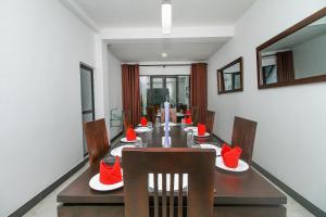 a dining room with a long table with red chairs at Delphin Hotel in Nuwara Eliya